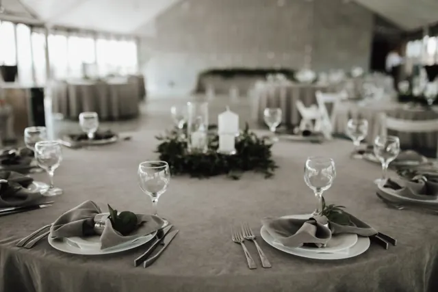 Table ronde au nappage gris, couronne de verdure et bougies blanches
